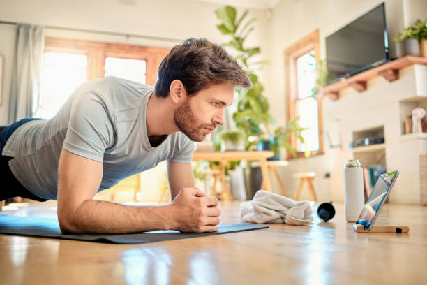 istock One fit young caucasian man doing elbow plank hold bodyweight exercise while training with online tutorial on digital tablet at home. Focused guy gaining muscle, increase endurance, enhance upper body and core strength during workout 1400692918