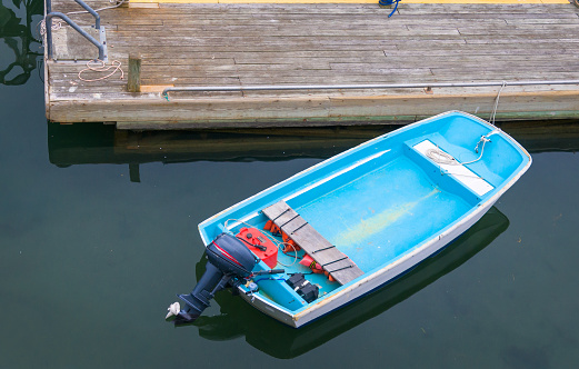 A single blue motor boat is ties to an old wooden dock in Bar Harbor, Maine