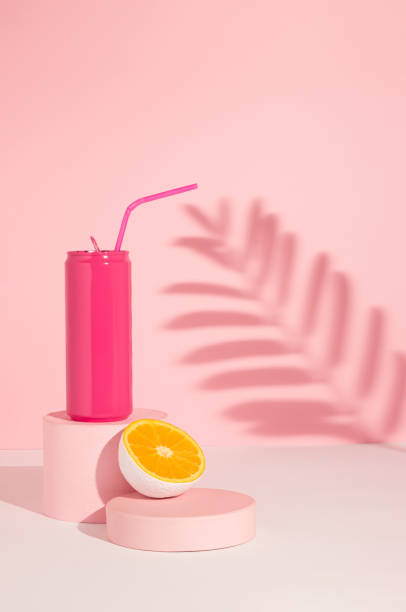 pink colored can with cut in half orange fruit on product podium and shadow. summer drink minimal concept. pink aesthetic. - business styles foods and drinks drinking imagens e fotografias de stock
