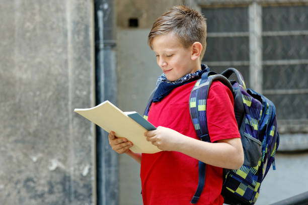 istock Young boy, elementary school student, reading books after school on his way home, enjoying a sunny day with his favorite literature 1400707564