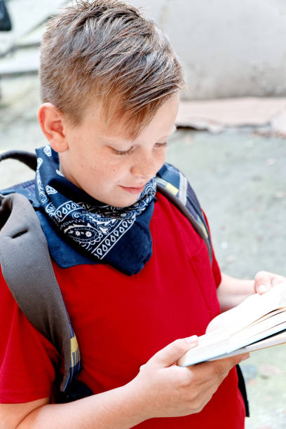 istock Young boy, elementary school student, reading books after school on his way home, enjoying a sunny day with his favorite literature 1400707607
