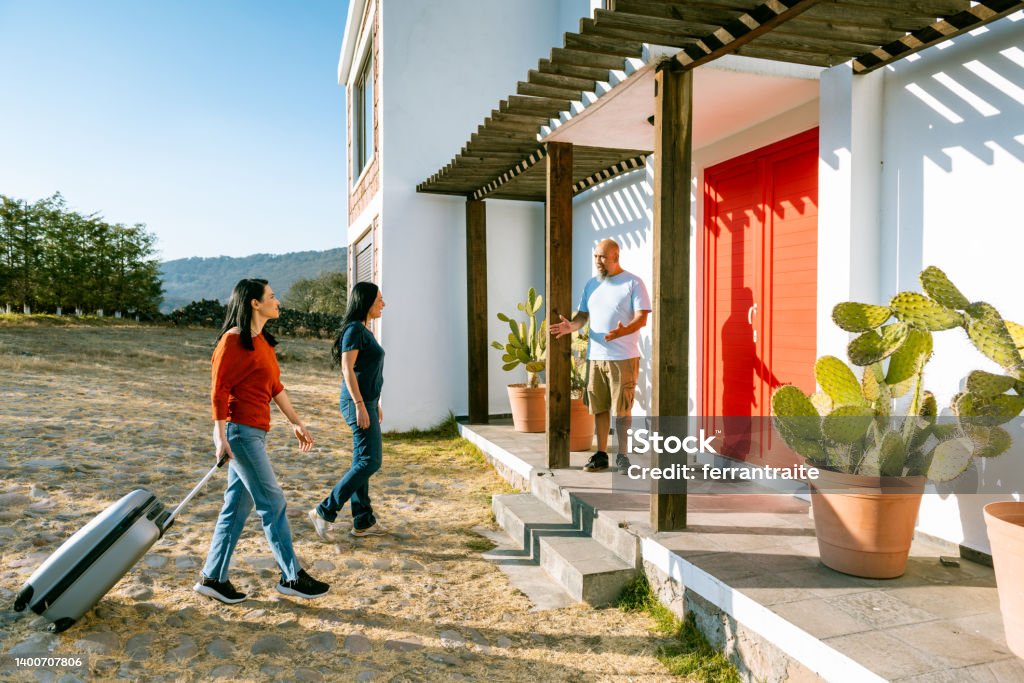 Female friends arrive at vacation rental Home owner welcoming lesbian couple arriving at vacation home Vacation Rental Stock Photo