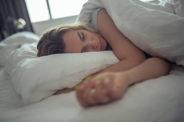 piękna kobieta śpi na białych prześcieradłach pokoju hotelowego. - pillow wake up yawning sleeping zdjęcia i obrazy z banku zdjęć