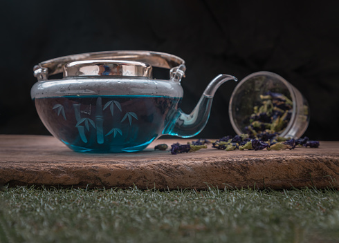 Glass teapot with Butterfly pea tea (Clitoria) or Organic blue anchan and Dry butterfly pea flower on Old wooden background. Healthy detox herbal drink, Selective focus.