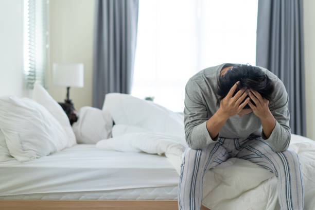 Asian young man feel angry girlfriend having conflict domestic problem. New marriage man and woman feel heartbroken for quarrel conflict while sit on bed in bedroom. Family problem-separation concept. stock photo