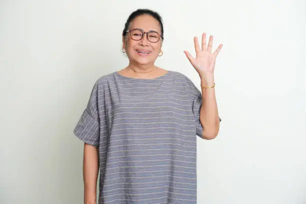 Elderly Asian women smiling to the camera while give five fingers sign