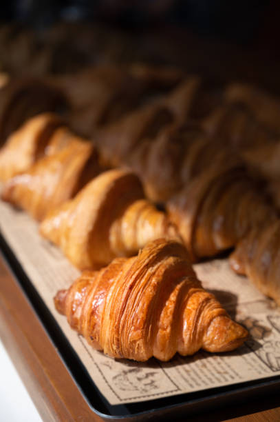 freshly baked croissants, golden brown on paper, ready to serve in the morning. - croissant imagens e fotografias de stock