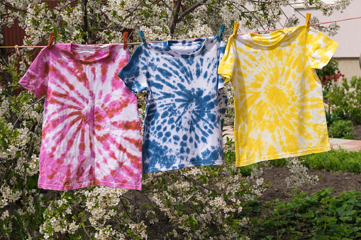 Drying three multi-colored T-shirts in tie dye style. Minimal fashion concept.