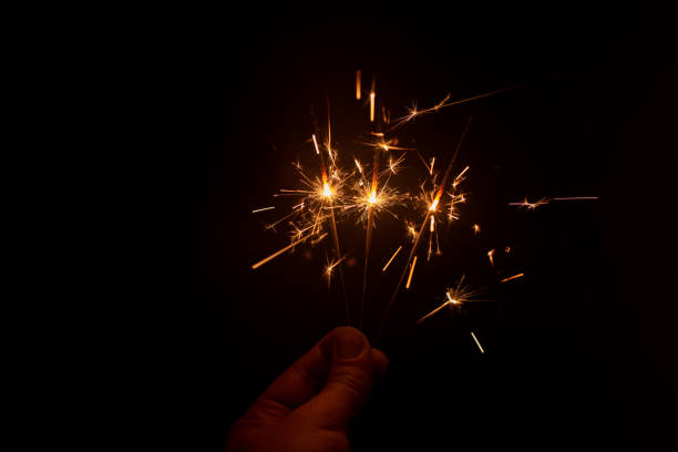 istock Fingers holding up bright sparked fireworks in dark 1400733526