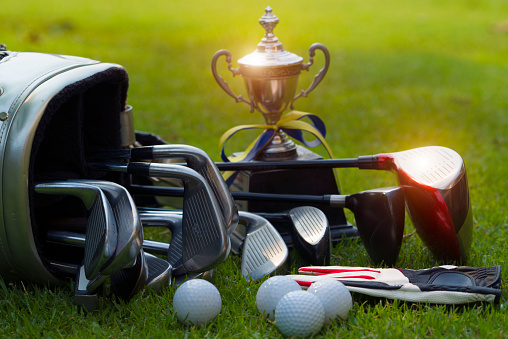 Closeup old golf bags on green. Set of golf clubs over green field background.