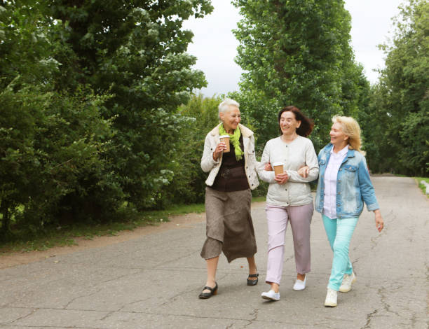 istock Three beautiful elderly women are walking in the park, having fun talking and drinking coffee. 1400736783
