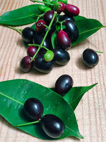 Fresh Jambolan plum or Java plum (Syzygium cumini) with leaf on wooden table.