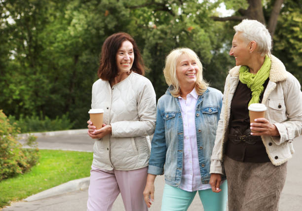 istock Three cheerful pensioners are walking in the park, having fun talking and drinking coffee. 1400737904