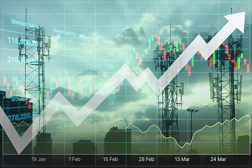 Silhouette of three communication poles and buildings on urban twilight sky with graph and chart for stock financial index and technology business presentation and report background.\