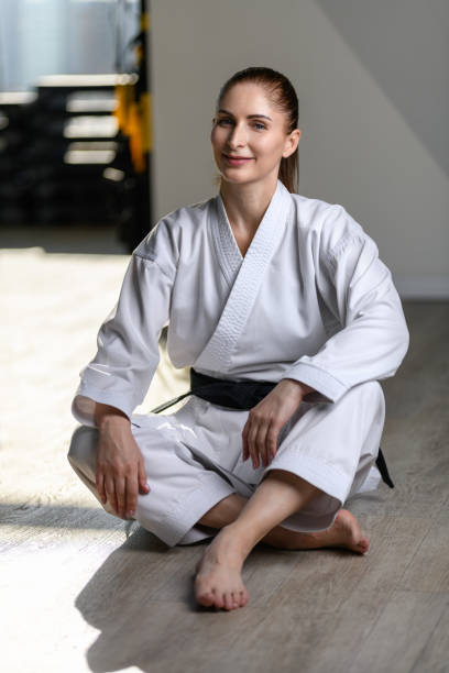 karaté fille avec ceinture noire en kimono squats. mode de vie sportif sain - martial arts women tae kwon do black belt photos et images de collection