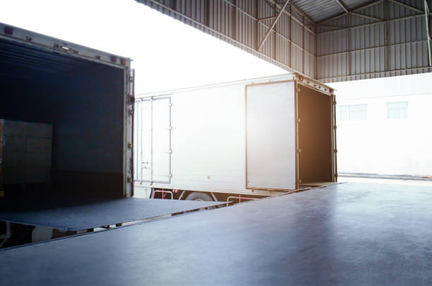 istock Cargo Container Trucks Parked Loading Dock at Distribution Warehouse. Shipping Trucks. Lorry. Cargo Freight Trucks Transport Logistics. 1400748418