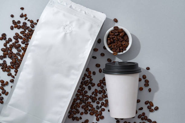 istock Cup of coffee with coffee beans on paper background. Top view 1400749471