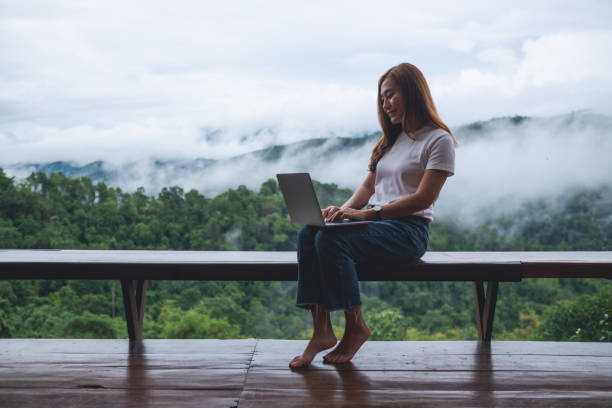 istock A young woman using and working on laptop computer while sitting on balcony with a beautiful nature view on foggy day 1400750656