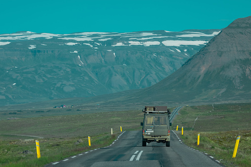 Rear view of an adventure offroad vehicle traveling through icelandic roads towards the mountains. Epic roadtrip with a car or overlanding vehicle.