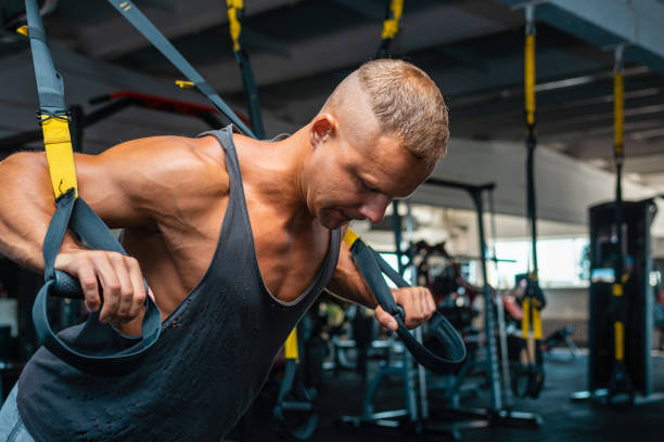 Young and strong man doing push ups with trx fitness straps at a gym.Close up. Young and strong man doing push ups with trx fitness straps at a gym.Close up. suspension training stock pictures, royalty-free photos & images