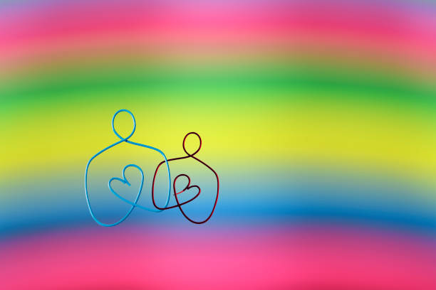 Two people made of wire against rainbow background with copy space.