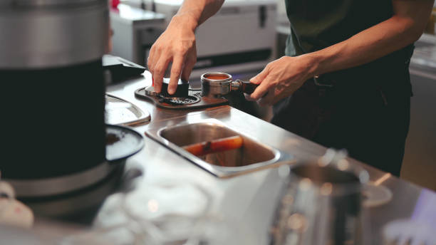 Barista making Coffee beans in a portafilter by the coffee grinder