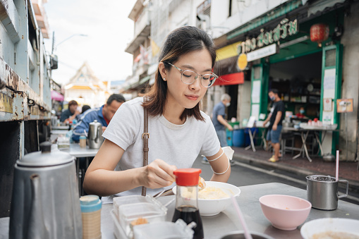 Young Generation Y Asia female people happy weekend Pov eating Kuay Jap noodles street food in chinatown yaowarat bangkok thailand