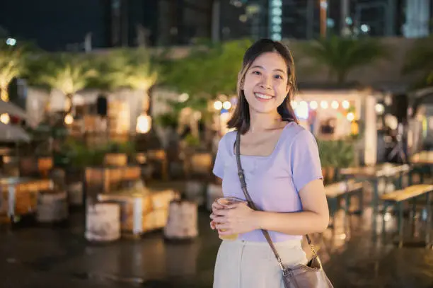 Young cheerful chinese thailand female exploring foodie walking on modern nightmarket bangkok thailand