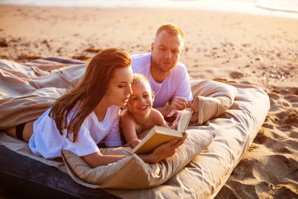istock Mom is reading a book to her son while lying on the bed. 1400760981
