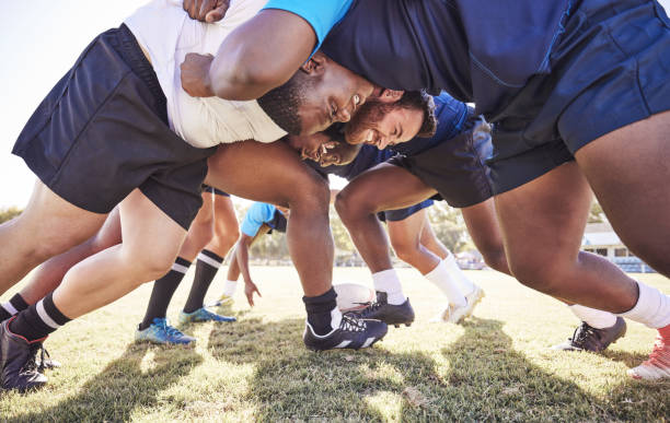 below two opponent rugby teams contesting a scrum during a match outside on a field. rugby players battling and fighting to win the ball while competing for possession in a game. strength and power - rugby scrum stockfoto's en -beelden