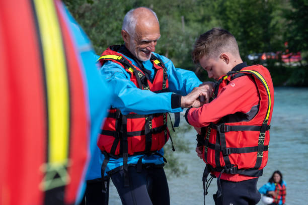 istock Man helping boy to fasten a life jacket 1400768486