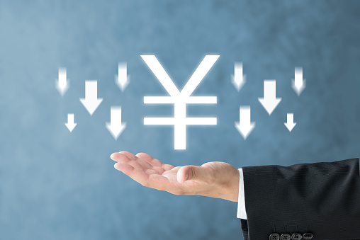 Business man's hand and Japanese yen mark with downward arrows