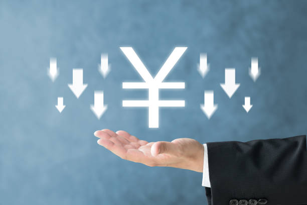 Business man's hand and Japanese yen mark with downward arrows stock photo
