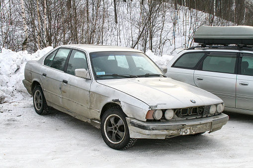 Asha, Russia - January 4, 2011: Old damaged German saloon car BMW 5-series (E34) at a snow covered countryside.