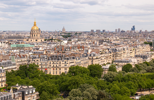 A vintage looking skyline photo taken in Paris France. The Eiffel Tower is to the right of the frame with dramatic clouds in the sky as a background.