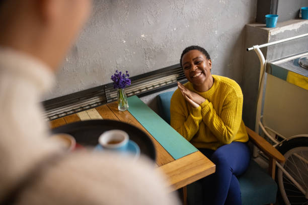 camarera que atiende a clientes femeninas de etnia negra en la cafetería - service occupation candid small business carrying fotografías e imágenes de stock