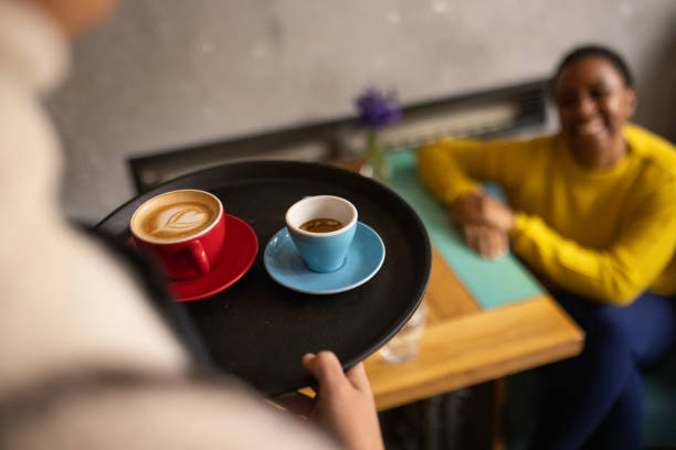 Unrecognizable waitress Japanese ethnicity serving female customer Black ethnicity at the coffee shop