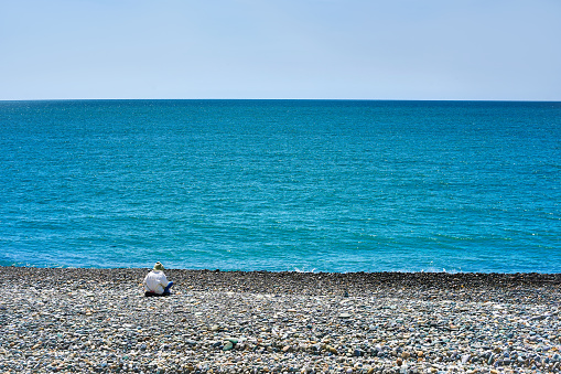 Lonely woman sitting on the beach near the sea. High quality photo