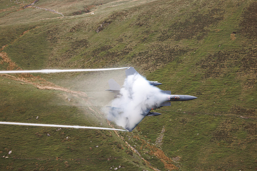 Wales, United Kingdom - 25th May 2022 - US Air Force F15 fighter jet performs low flying through the mountains of the Mach Loop