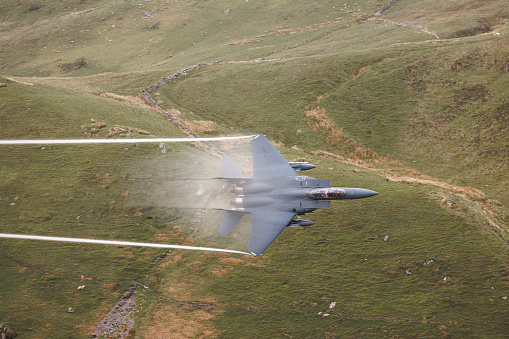 Wales, United Kingdom - 25th May 2022 - US Air Force F15 fighter jet performs low flying through the mountains of the Mach Loop