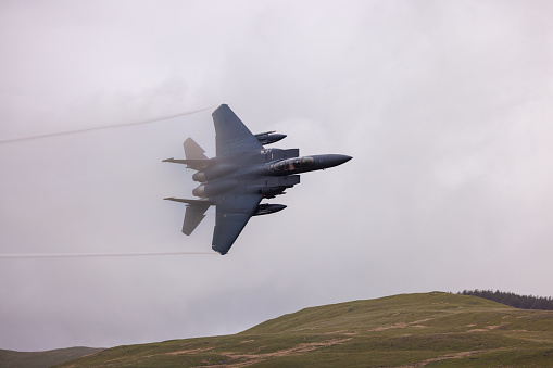 Wales, United Kingdom - 25th May 2022 - US Air Force F15 fighter jet performs low flying through the mountains of the Mach Loop