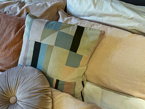 Stock photo showing a close-up view of a heap of scatter cushions piled on a bed.