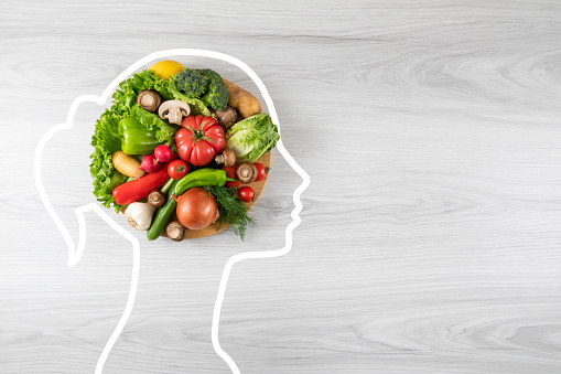 Healthy eating concept with vegetable and human head drawing on gray wooden background with copy space