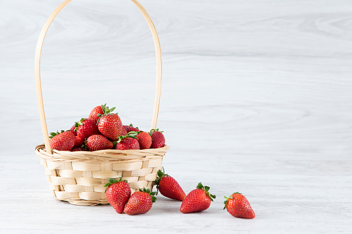 Fresh ripe strawberries in a white bowl on a white wooden background