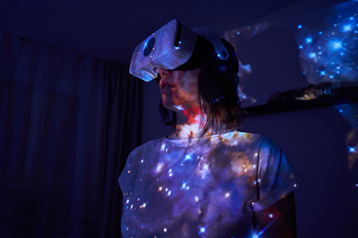 Woman is using virtual reality headset. Elements of this image furnished by NASA. Concept of virtual, augmented and extended reality, artificial intelligence and cyber security