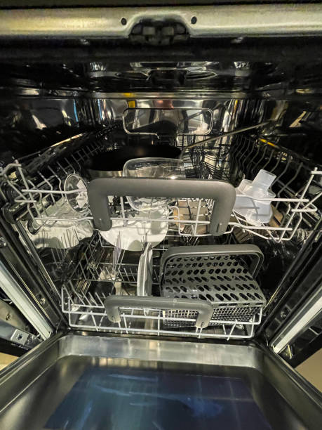 istock Image of interior of dishwasher with empty, plastic, cutlery basket, half full machine with clean frying pan and wine glass ready to be put away after being washed and dried 1400778399