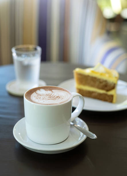istock cup of hot coffee art with cake on wooden table in cafe 1400779810