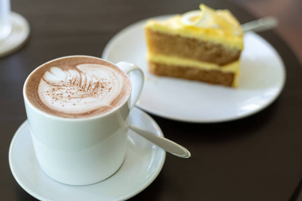 istock cup of hot coffee art with cake on wooden table in cafe 1400779817