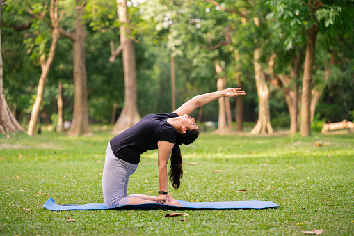 Active senior Indian woman doing yoga asana and morning exercise at park