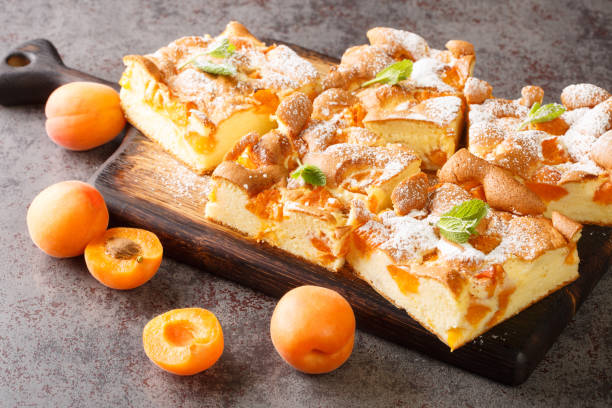 istock Delicate cake with apricot with mint and dusted with icing sugar closeup on a rustic wooden board. Horizontal 1400780769